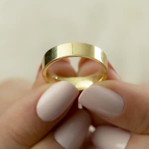 Può includere: Una semplice fede nuziale d'oro tenuta nelle mani di una persona.