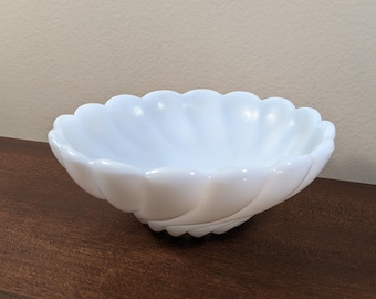 May include: A white milk glass bowl with a scalloped edge. The bowl is small and has a fluted design.
