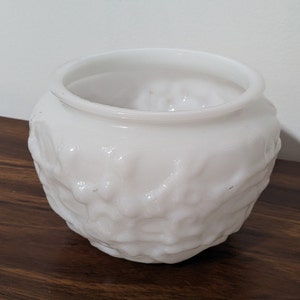 May include: White milk glass planter with a textured, raised design. The planter is round and has a wide opening.