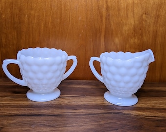 May include: A white milk glass creamer and sugar bowl set with a textured, bubble-like design.