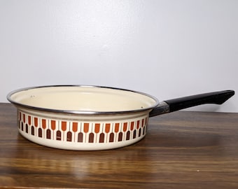 May include: A vintage enamel saucepan with a brown and orange geometric pattern. The saucepan has a black plastic handle.