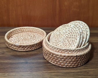 May include: Set of six woven round coasters in a natural beige color, stacked inside a matching woven basket.