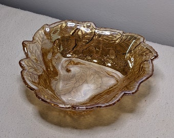 May include: A small amber glass bowl with a leaf design. The bowl has a scalloped edge and a footed base.