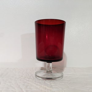 May include: A red glass goblet with a clear glass stem and base.