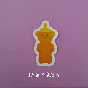 May include: A honey bear sticker with a yellow squeeze bottle top. The sticker is 1.4 inches by 2.5 inches.