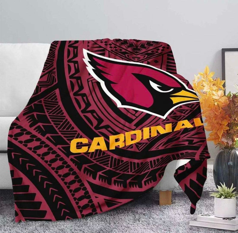 May include: A red and black throw blanket with a tribal pattern and the Arizona Cardinals logo. The logo is in red and white with a yellow beak and the word "CARDINALS" in yellow letters.