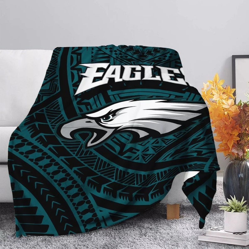 May include: A teal and black fleece blanket with a white eagle graphic and the word "EAGLES" in white. The eagle graphic has a tribal pattern around it.
