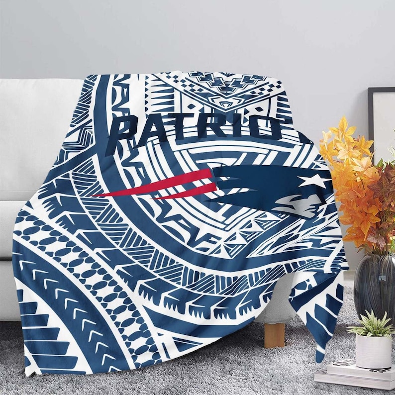 May include: A blue and white throw blanket with a Polynesian-style pattern and the word "PATRIOTS" in bold letters. The blanket features a red and blue logo with a bird design.