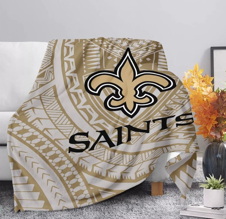 May include: A brown and white throw blanket with a gold fleur-de-lis and the word "Saints" in black lettering. The design is a tribal pattern.