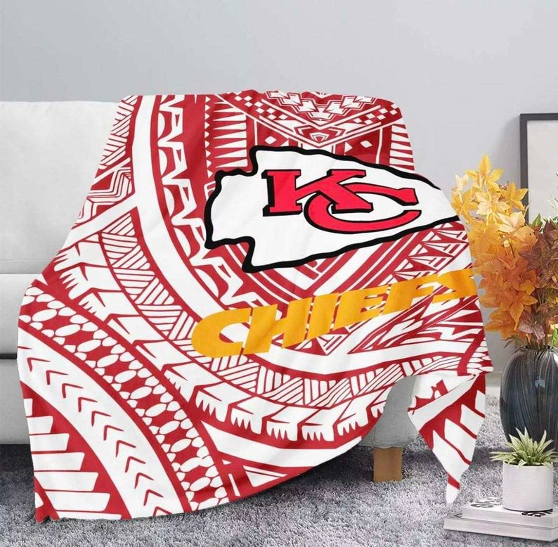 May include: Red, white, and gold throw blanket with a tribal pattern and the Kansas City Chiefs logo. The logo features the letters "KC" in red and white with a red arrowhead behind it. The words "Chiefs" are in gold letters.