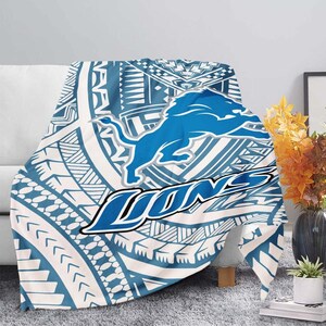 May include: A blue and white throw blanket with a tribal pattern and a blue lion logo with the word "LIONS" in a blue arc.