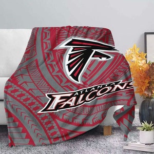 May include: Red, gray, and black fleece blanket with a tribal pattern and the Atlanta Falcons logo. The logo features a red and black falcon head with the words "Atlanta Falcons" written below.