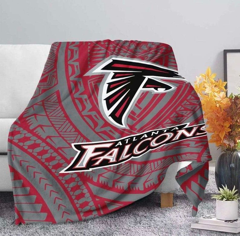 May include: Red, gray, and black fleece blanket with a tribal pattern and the Atlanta Falcons logo. The logo features a red and black falcon head with the words "Atlanta Falcons" written below.