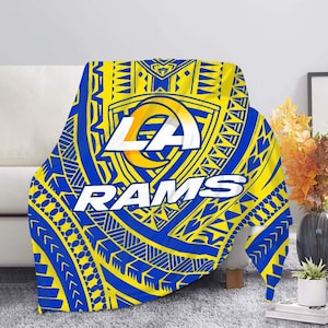 May include: A blue and yellow throw blanket with a tribal pattern and the Los Angeles Rams logo. The logo features the letters "LA" in a white circle with a yellow outline, and the word "RAMS" in white letters below the circle.