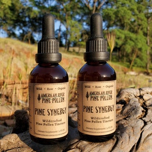 May include: Two brown glass bottles with dropper tops containing a pine pollen tincture. The bottles are labeled "American River Pine Pollen" and "Pine Synergy Wildcrafted Pine Pollen Tincture".