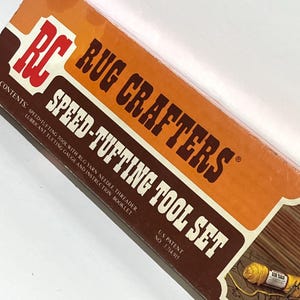 May include: A rectangular cardboard box for a Rug Crafters Speed-Tufting Tool Set. The box features orange and dark brown colors with white text reading Rug Crafters Speed-Tufting Tool Set, U.S. Patent No. 3,714,915, and a list of contents.