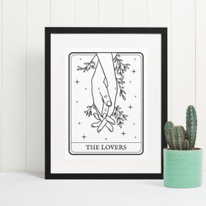 Könnte beinhalten: Schwarz-weiß-Illustration von zwei ineinander verschlungenen Händen mit Ranken und Sternen. Der Text "THE LOVERS" ist unter den Händen gedruckt.