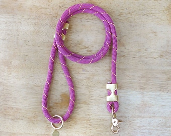 Peut inclure: Une laisse de chien en corde rose et or avec un mousqueton et un anneau dorés. La laisse est faite d'une corde épaisse et résistante.