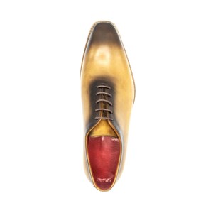 May include: A pair of yellow leather lace-up shoes with a red leather interior. The shoes have a pointed toe and a low heel.