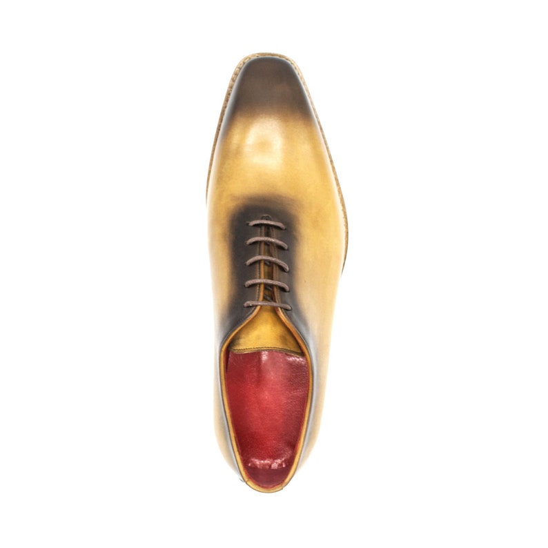 May include: A pair of yellow leather lace-up shoes with a red leather interior. The shoes have a pointed toe and a low heel.
