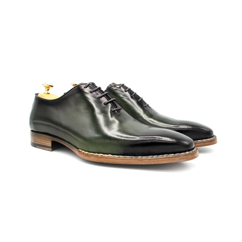 May include: A pair of green leather lace-up dress shoes with a brown sole.