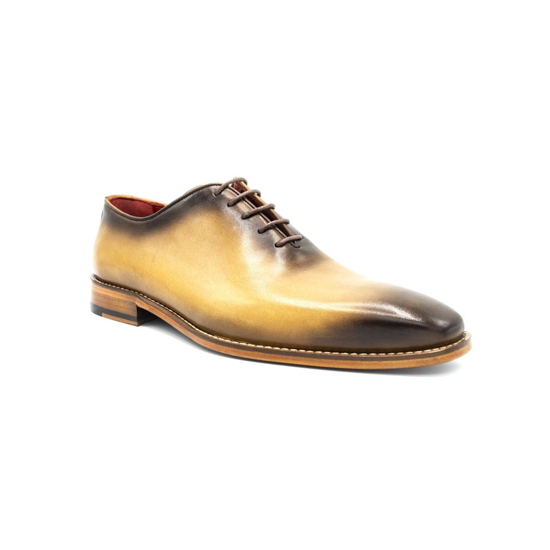 May include: A pair of brown leather lace-up shoes with a light brown ombre effect. The shoes have a rounded toe and a brown leather sole.