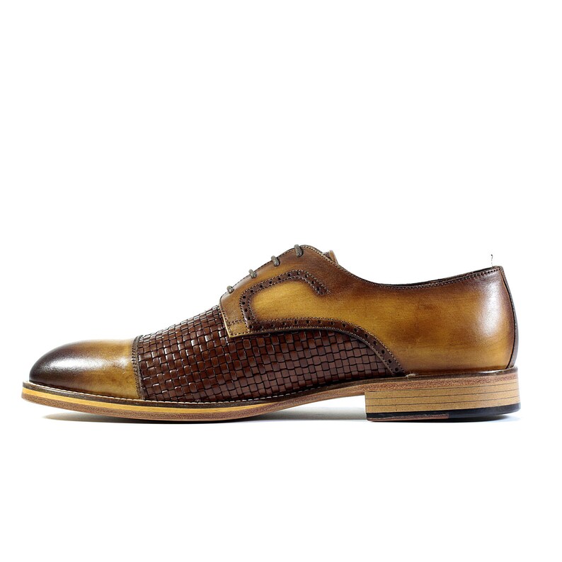 Puede incluir: Zapatos de vestir de cuero marr&oacute;n con un patr&oacute;n tejido en la puntera y una parte superior de cuero marr&oacute;n claro. Los zapatos tienen un cierre de cordones y una suela de cuero marr&oacute;n.