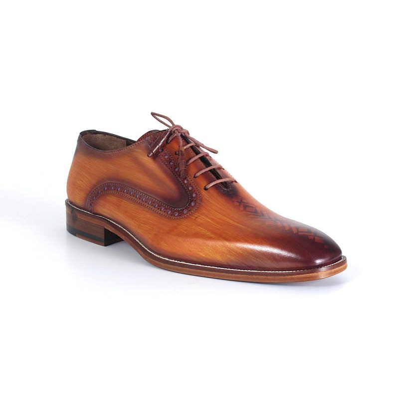 May include: Brown leather lace-up dress shoes with a brogue design and a subtle woodgrain pattern.