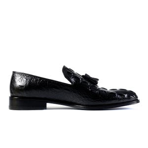 K&ouml;nnte beinhalten: Schwarzer Lederloafer mit strukturiertem, krokodil&auml;hnlichem Muster. Der Schuh hat ein kleines Quastendetail und einen niedrigen Absatz. Das gl&auml;nzende Finish verleiht diesem klassischen Schuhdesign einen Hauch von Eleganz.