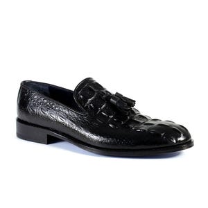 K&ouml;nnte beinhalten: Schwarzer Lederloafer mit Krokodiltextur und kleinem Quastendetail. Der Schuh hat einen niedrigen Absatz und eine runde Spitze. Ein klassischer Schuhstil.