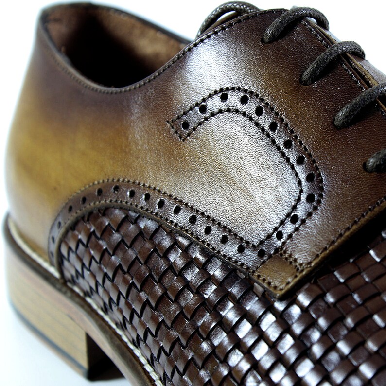 Puede incluir: Zapatos de vestir de cuero marr&oacute;n con un patr&oacute;n de cuero tejido en la punta y un dise&ntilde;o de brogue en la parte superior del zapato.