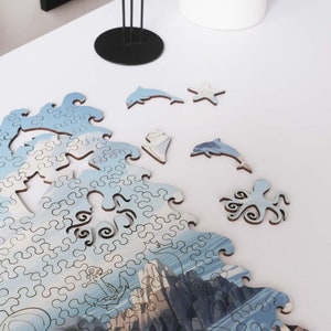 May include: A blue and white jigsaw puzzle depicting a seascape with an octopus, dolphins, and a starfish. The puzzle pieces are scattered on a white surface.