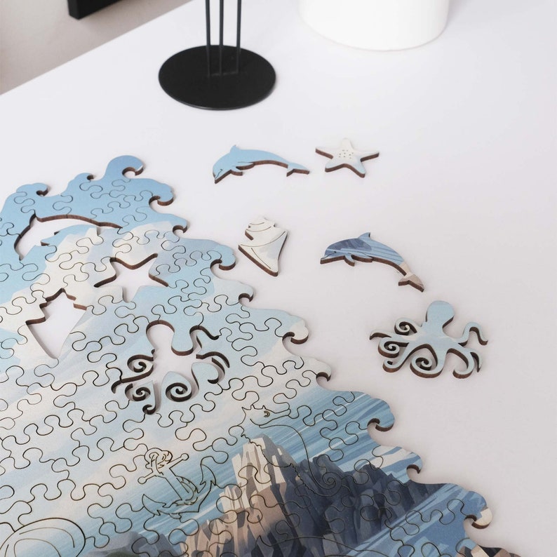 May include: A blue and white jigsaw puzzle depicting a seascape with an octopus, dolphins, and a starfish. The puzzle pieces are scattered on a white surface.