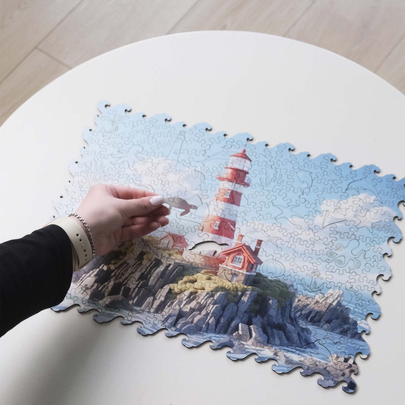 May include: A completed jigsaw puzzle of a red and white lighthouse on a rocky island. The puzzle pieces are shaped like waves and the image is set against a blue sky with white clouds.