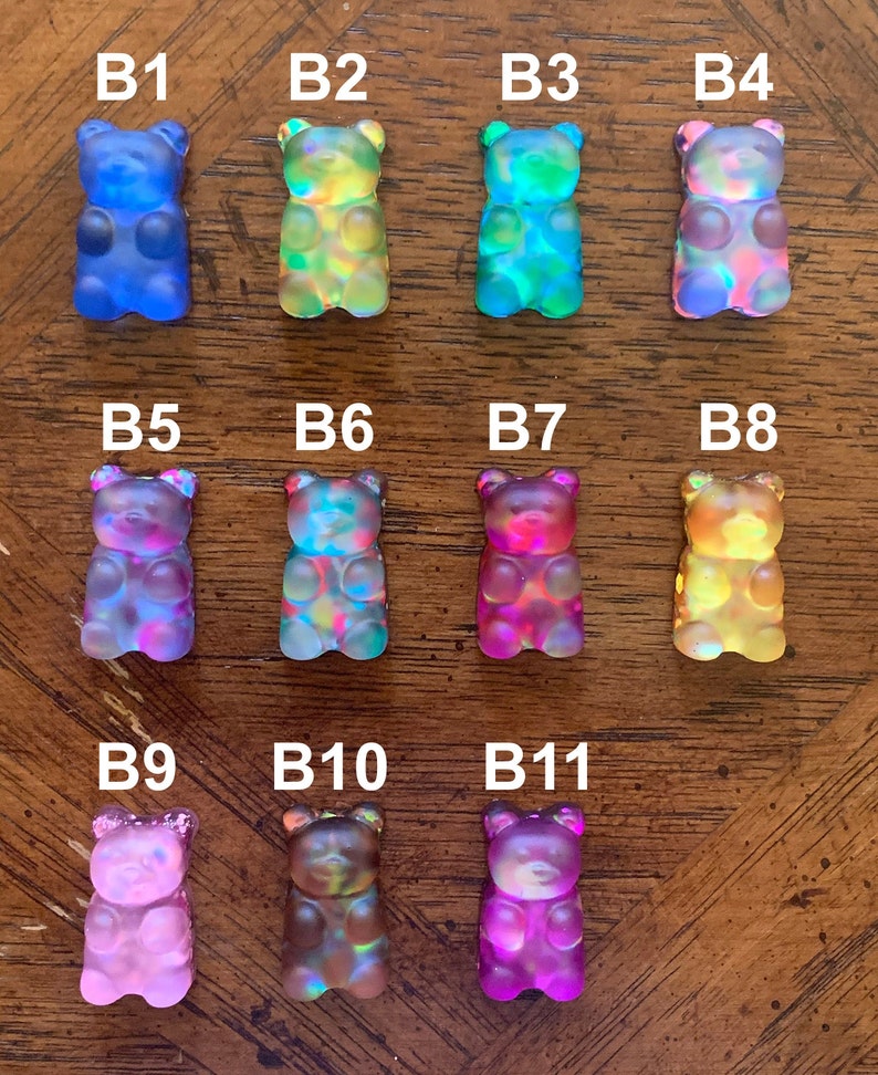 May include: An assortment of eleven colorful gummy bear figurines. Each bear is a different color, including blue, green, pink, and yellow. The bears are arranged in three rows, with the letters B1 through B11 above each bear.