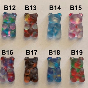 May include: Eight colorful gummy bear-shaped resin charms. Each charm is a different color, including blue, green, red, and purple. The charms are labeled B12 through B19. These charms are ideal for jewelry making or other craft projects.