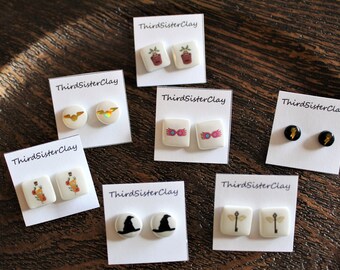 May include: Eight pairs of Harry Potter themed earrings on white cards with the text "ThirdSisterClay". The earrings feature images of a plant, glasses, a lightning bolt, a bat, a potion bottle, a hat, and a wand.