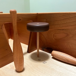 May include: A wooden game with three wooden bowling pins and a brown wooden ball. The game has a number 10 printed on the surface.
