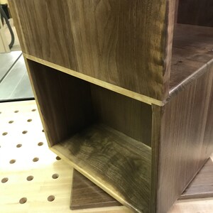 以下が含まれることがあります： 濃い茶色の仕上げのウッドシェルフユニット。棚はオープンシェルフが1つあり、無垢材で作られています。