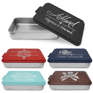 May include: Set of five personalized 9x13 inch baking pans with lids. The lids are black, red, blue, turquoise, and brown with various engraved designs. The designs include text, a heart, a coffee shop logo, a monogram, and a chef's hat with crossed utensils.