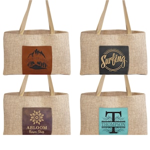 May include: Four burlap tote bags with different designs on the front. The first bag has a brown leather patch with a mountain scene and the text "Lazy River Lodge". The second bag has a black leather patch with the text "Surfing" in gold lettering. The third bag has a brown leather patch with a flower design and the text "Abloom Flower Shop". The fourth bag has a turquoise leather patch with a black letter "T" and the text "Thompson".