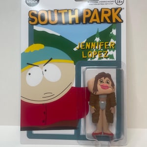 May include: South Park action figure featuring Jennifer Lopez, packaged on a card with the show's logo and character art. The figure is in a clear plastic case, with the text "OUT OF STOCK" and "AGES 18+" visible.