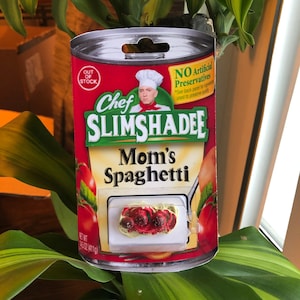 May include: A red and yellow can with a white label that says "Chef Slim Shadee Mom's Spaghetti". The can has a picture of a chef with a red hat and a white shirt. The can is out of stock. There is a small plastic container with a red and yellow spaghetti and meatballs inside.
