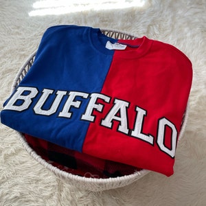 May include: A red and blue sweatshirt with the word "BUFFALO" in white lettering across the front.