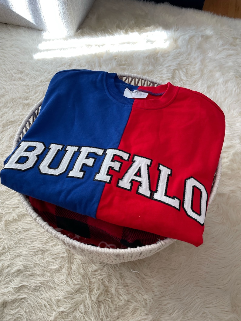 May include: A red and blue sweatshirt with the word "BUFFALO" in white lettering across the front.