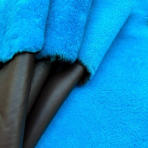 Peut inclure: Gros plan sur deux échantillons de tissu en cuir marron pliés sur un échantillon de tissu bleu turquoise brillant. Les échantillons de tissu sont doux et duveteux.