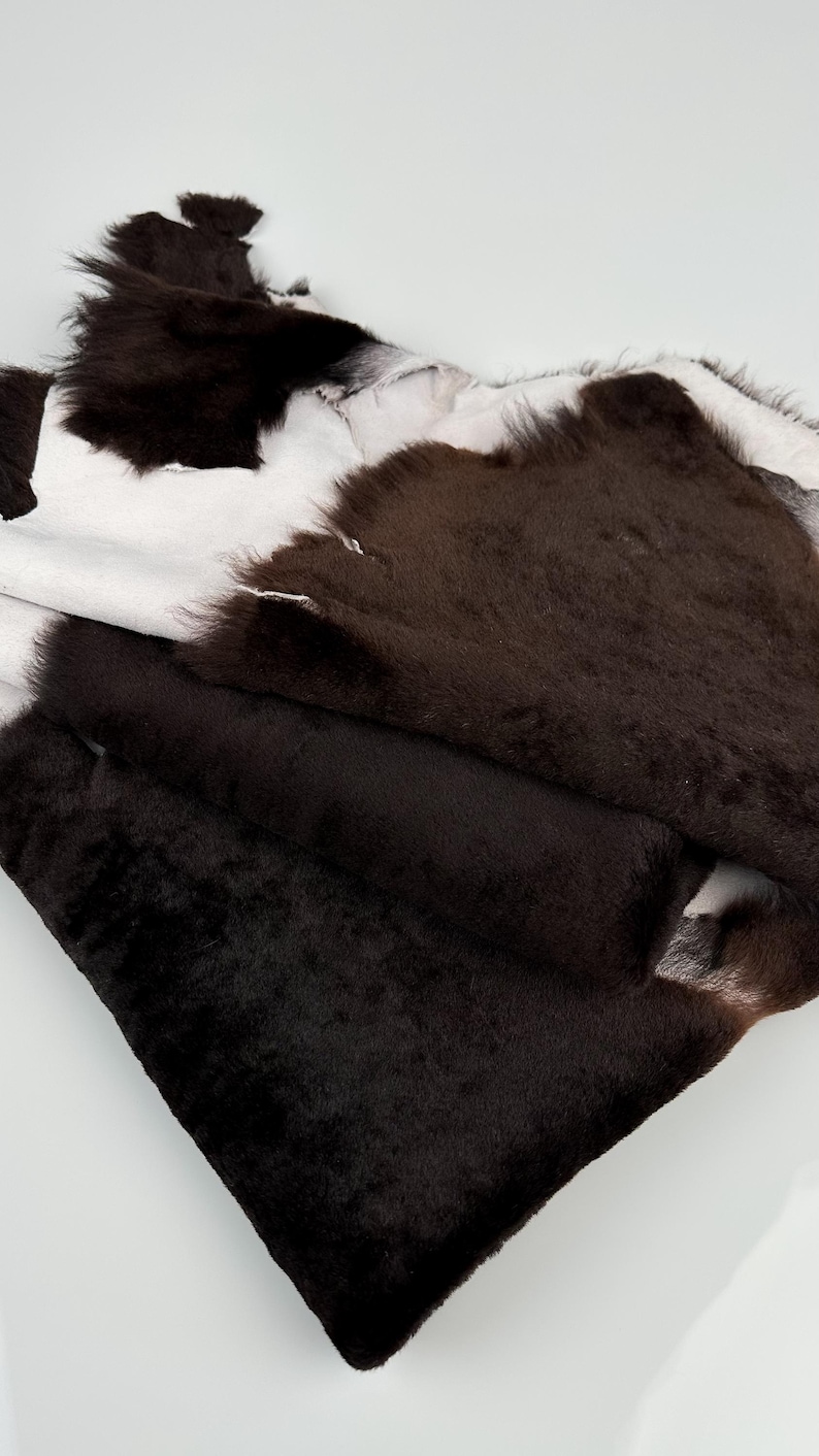 May include: A brown and white cowhide rug with a soft, plush texture. The rug is folded in half, revealing the white underside.