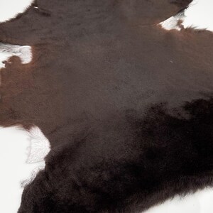 May include: A brown and white cowhide rug with a soft, fuzzy texture.