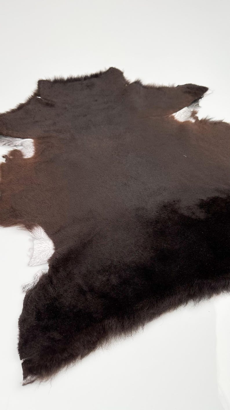 May include: A brown and white cowhide rug with a soft, fuzzy texture.