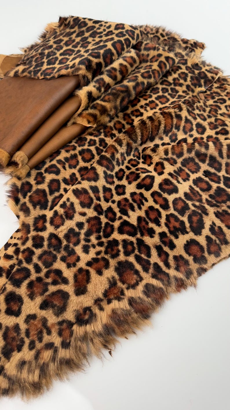 May include: A brown and black faux fur fabric with a leopard print pattern. The fabric has a soft, fluffy texture and is ideal for crafting projects.